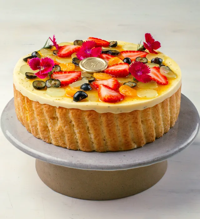 Charlotte de maracujá com biscoitos champanhe em volta e frutas frescas e flores por cima