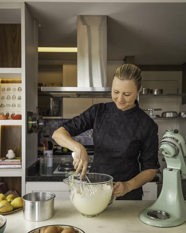 Karyne batendo creme no fouet, na bancada da cozinha da Aula de Confeitaria
