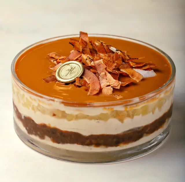 Pavê de abacaxi em travessa de vidro, com camadas de creme e cobertura de caramelo com lascas de coco